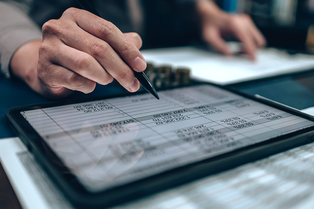 A person examining financial documents on a tablet.