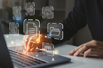 Businessman working on laptop with abstract images representing different resources floating in the air above the laptop.