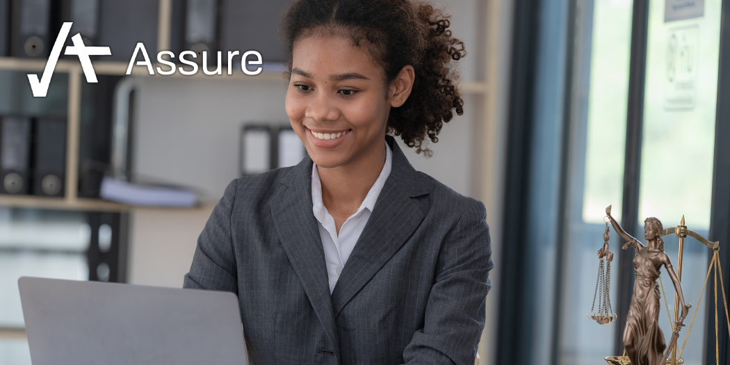 A photo of a young, black, woman lawyer in an office using a laptop. In the top left is the Assure logo.