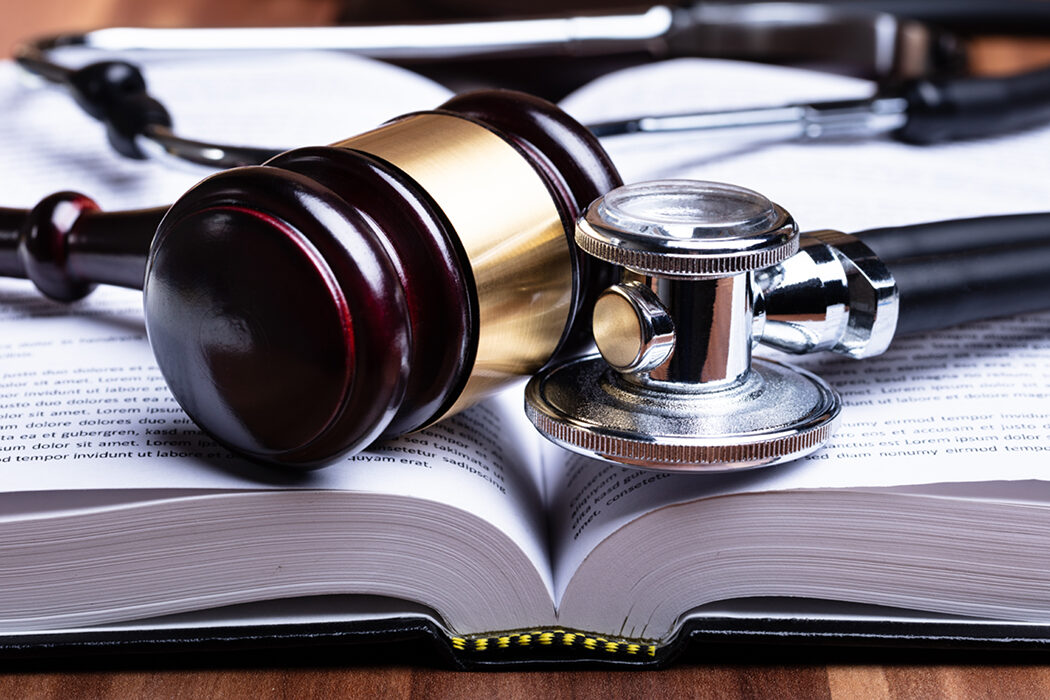 Close up of a gavel and stethoscope on an open book.