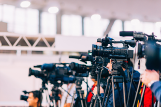 An array of cameras and microphones at a press conference