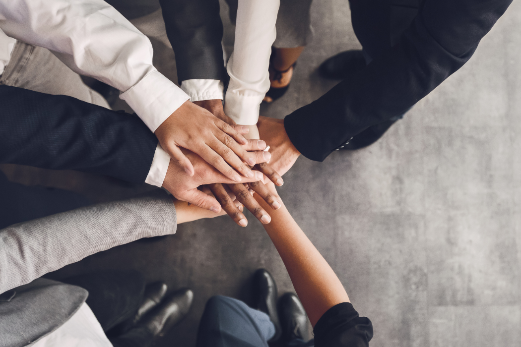 Top-down view of people in a semi-circle putting their hands in the center